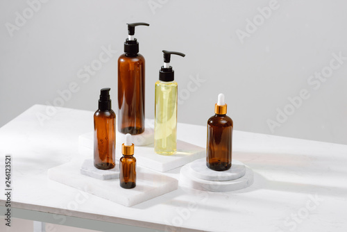 Spa cosmetics in brown glass bottles on gray concrete table. Copy space for text. Beauty blogger, salon therapy, branding mockup, minimalism concept