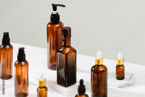 Spa cosmetics in brown glass bottles on gray concrete table. Copy space for text. Beauty blogger, salon therapy, branding mockup, minimalism concept