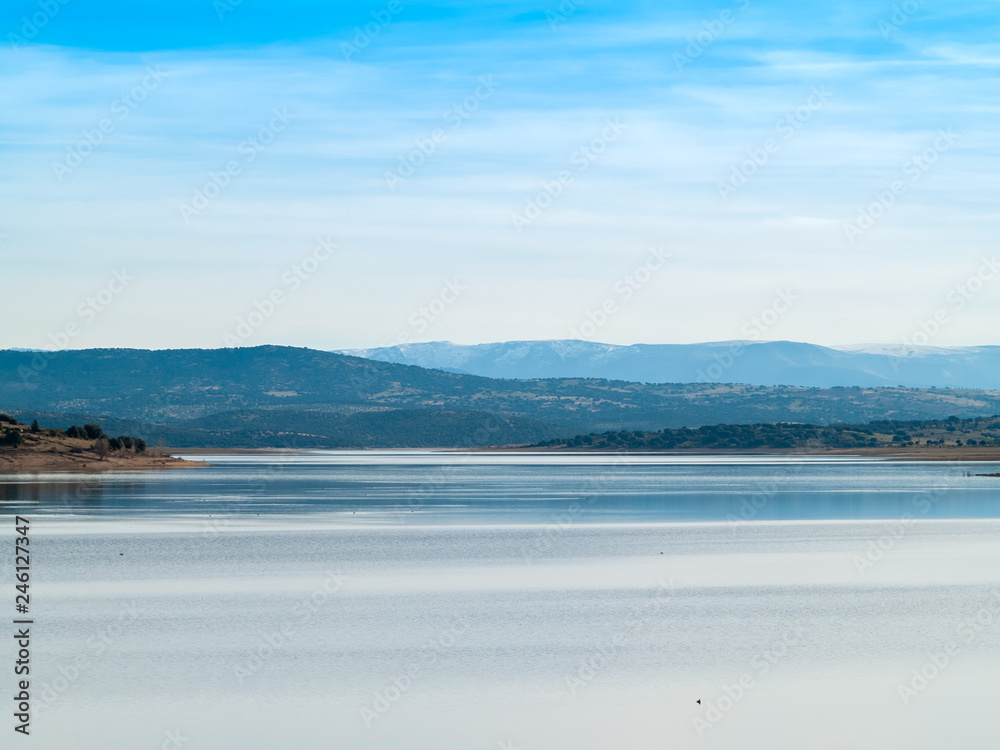 Landscape of a reservoir and mountains in a day with fog and clouds and birds swimming and flying in in La Maya Reservoir (Salamanca)