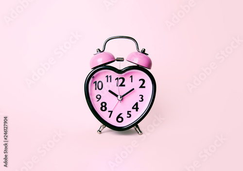 Heart shaped clock on pink background.