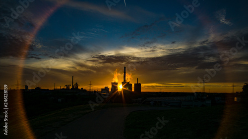 Industrie im Sonnenuntergang am Sommerabend mit Schornsteinen und Dampf am Sommerabend in Duisburg, Deutschland