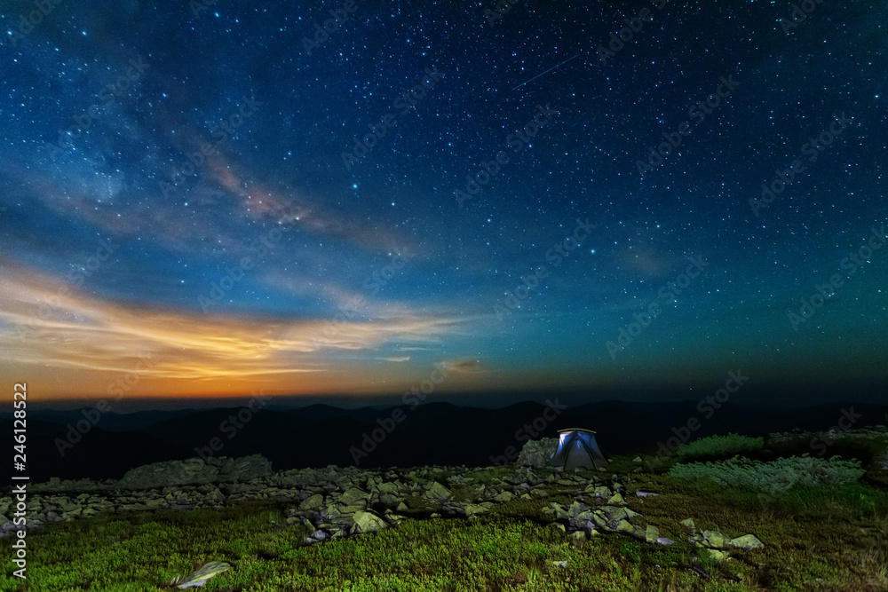 The starry sky in the mountains witha galaxy is a Milky way on the background of a tourist tent. The starry sky in the mountains witha galaxy is a Milky way on the background of a tourist tent.