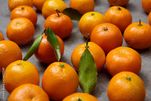 selective focus of orange tangerines with green leaves on grey table