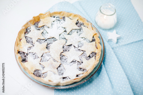 Homemade pie with stars on table with blue napkin and candle