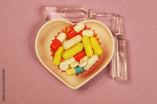 Pharmaceutical medicament, cure in container for health and heart on pink background.
