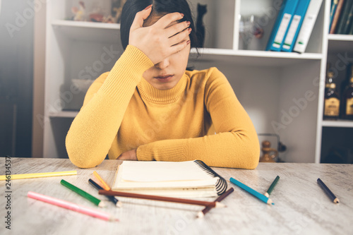 sad woman with notepad and pencils on table