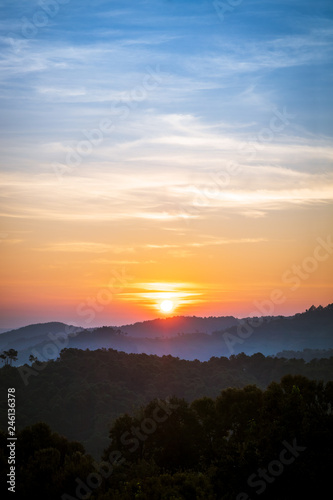 golden sunrise in the blue sky over silhouette of mountains © amstockphoto
