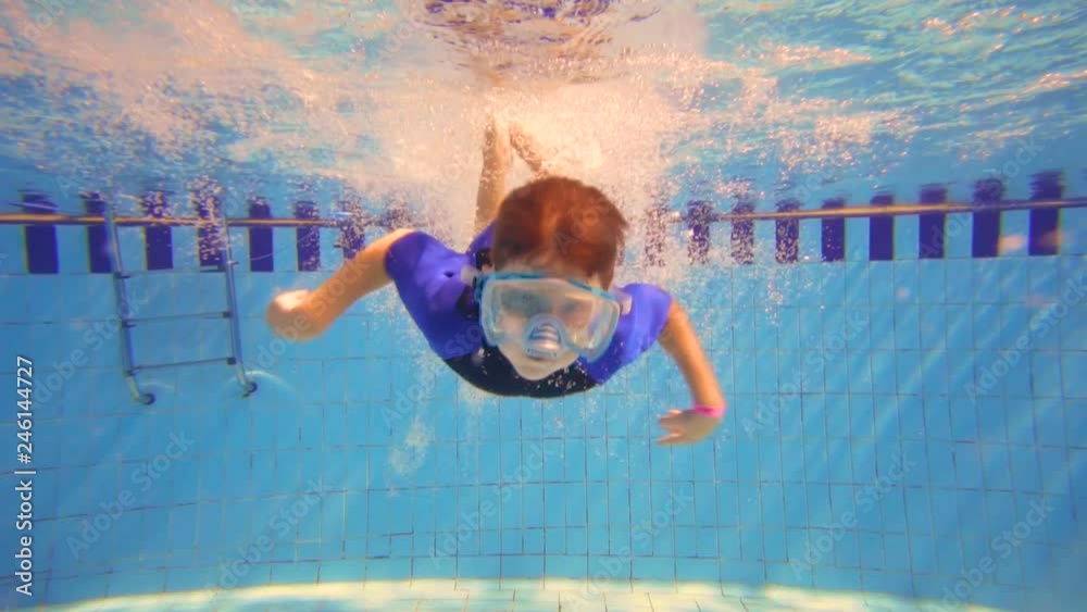 Boy in mask dive in swimming pool, underwater slow motion