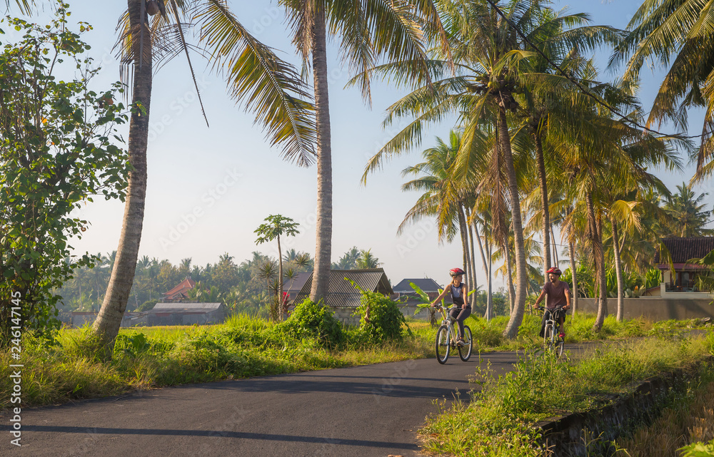 Couple riding a bicycle through the tropical island of Bali