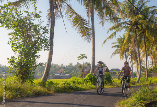 Happy young couple riding bicycles along road in summer. Leisure and lifestyle concept