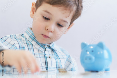 three years old boy puts money in a piggy bank, piggybank concept. mantesori space in the house