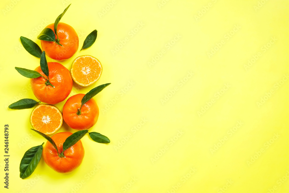 Close up image of juicy organic whole & halved tangerines with green leaves, visible core texture, isolated yellow background, copy space. Macro shot of bright citrus fruit slices. Top view, flat lay. Close up image of juicy organic whole & halved tangerines with green leaves, visible core texture, isolated yellow background, copy space. Macro shot of bright citrus fruit slices. Top view, flat lay.