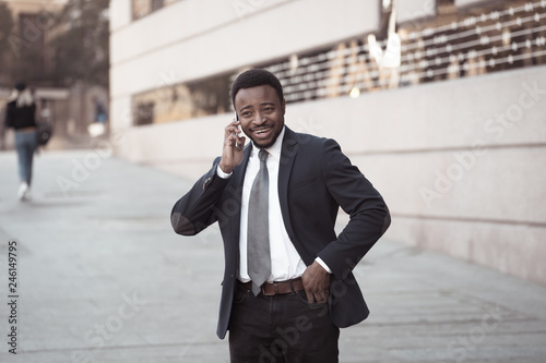 Portrait of handsome african american businessman walking in the city talking on mobile phone