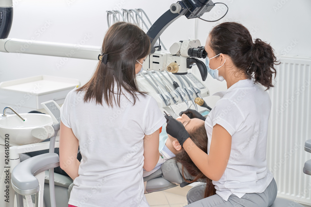 Obraz premium View from back of dentists and checking teeth of patient