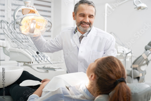 Cheerul dentist smiling  looking at patient.