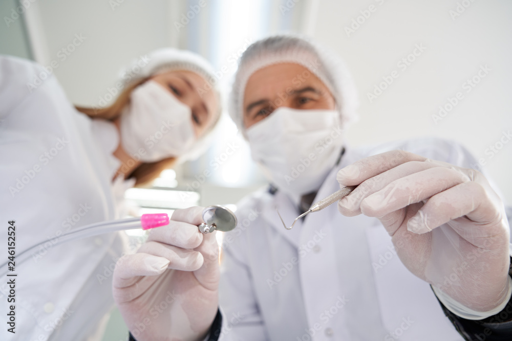 Two stomatologists looking at patient during examination. Two stomatologists looking at patient during examination.
