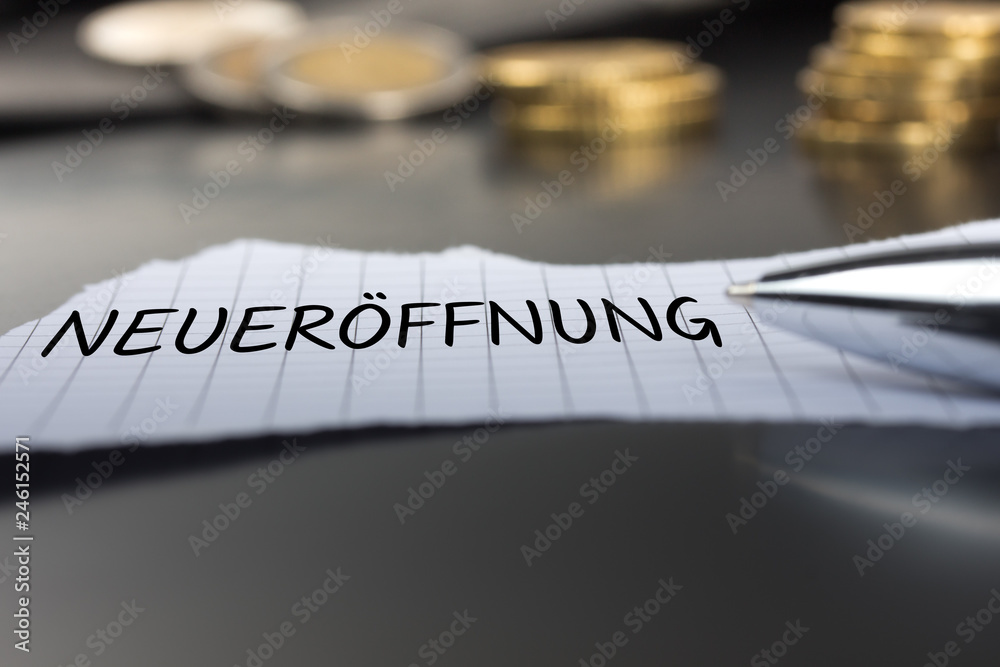 Fototapeta premium Neueröffnung auf einem Zettel mit Stift vor Geldmünzen
