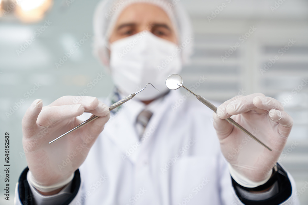 VIew from below of dentist in mask holding instruments. VIew from below of dentist in mask holding instruments.