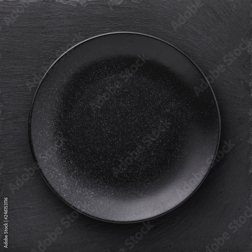 Empty ceramic plate in black on a stone stand, top view