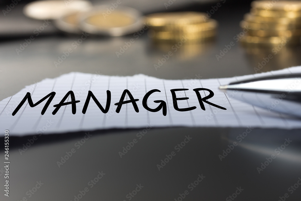 Manager auf einem Zettel mit Stift vor Geldmünzen Manager auf einem Zettel mit Stift vor Geldmünzen