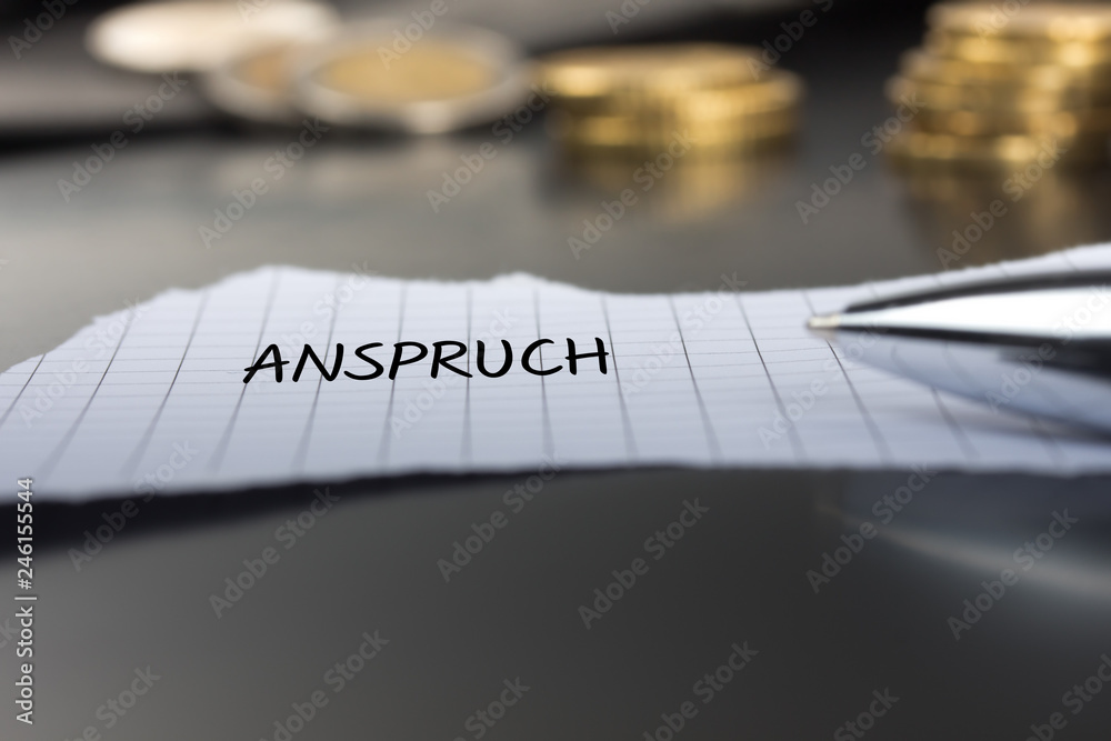 Anspruch auf einem Zettel mit Stift vor Geldmünzen Anspruch auf einem Zettel mit Stift vor Geldmünzen