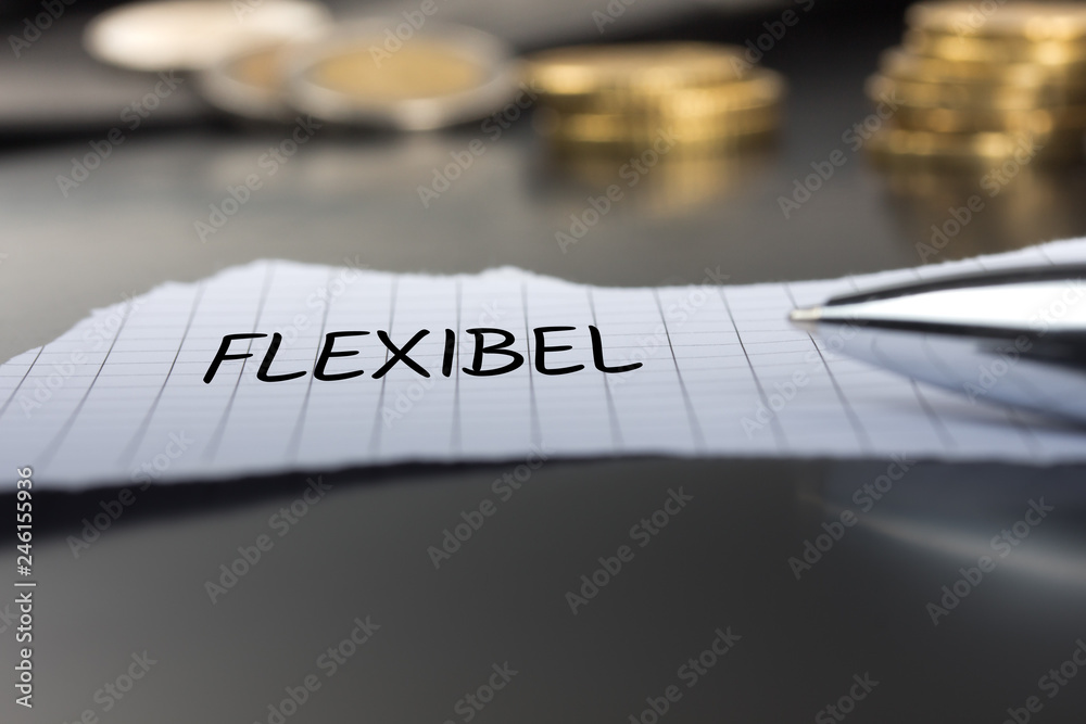 Flexibel auf einem Zettel mit Stift vor Geldmünzen Flexibel auf einem Zettel mit Stift vor Geldmünzen