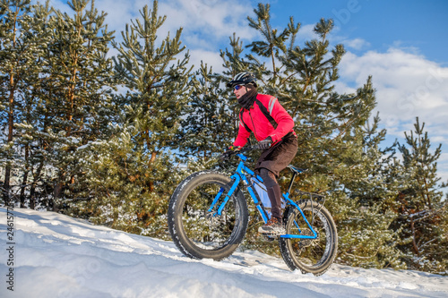 Man riding a mountain bike with big fat tires and helmet on a snow. Fat bike.
