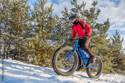 Man riding a mountain bike with big fat tires and helmet on a snow. Fat bike.