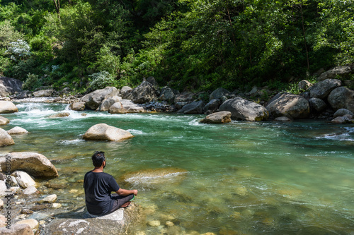 Fototapeta Naklejka Na Ścianę i Meble -  Man meditating yoga outdoor near the smooth flowing river with crystal clear water