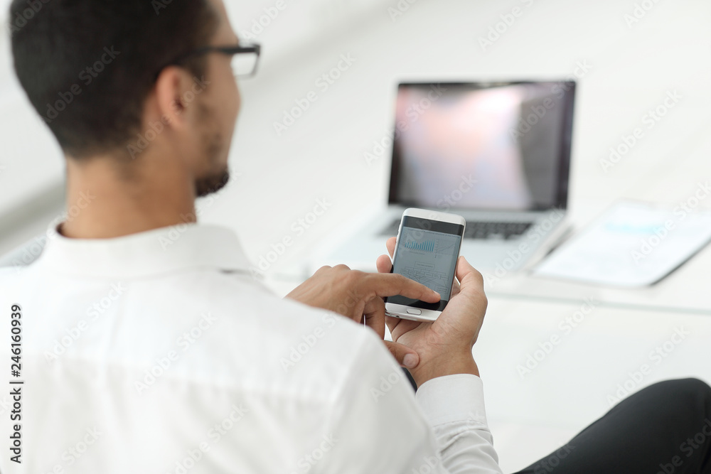 rear view. modern man browsing media files on his smartphone rear view. modern man browsing media files on his smartphone