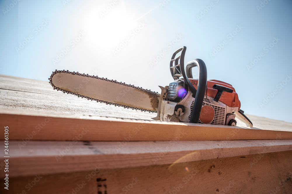 chainsaw lying on a roof, sunflares in background