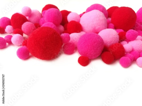 Variety size pom pom made from pink and red fiber yarn placed mix together on white background, There is copy space for your text.