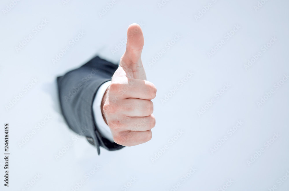 businessman breaks through the paper and shows his thumb up