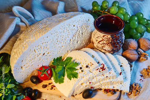 homemade Georgian Imeretian cheese on a wooden Board, cherry tomatoes, walnuts, grapes, spices