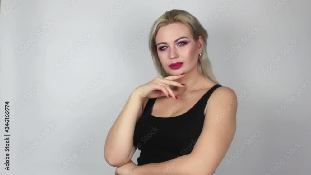 Blonde with bright makeup looking at the camera and smiling, on a white background in the studio Blonde with bright makeup looking at the camera and smiling, on a white background in the studio