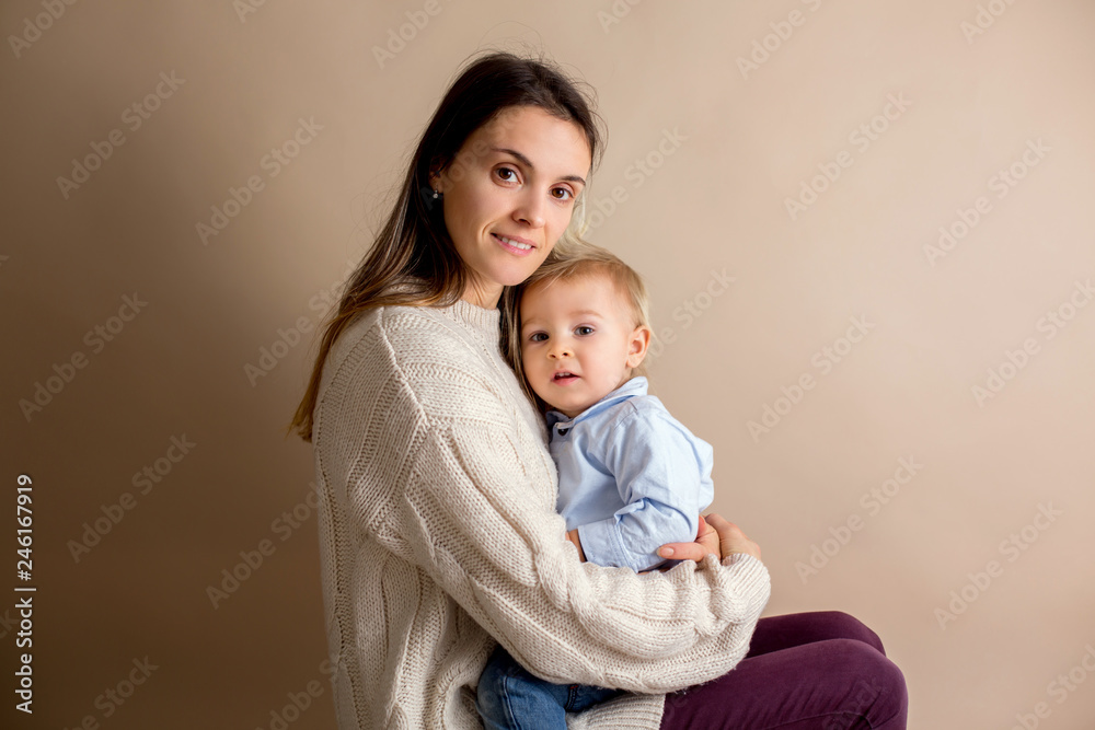 Happy young mother with a toddler child on light beige background
