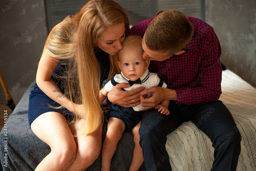 Young parents kiss their little son. Young parents kiss their little son.