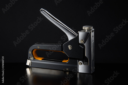 The furniture stapler on black background close-up. photo