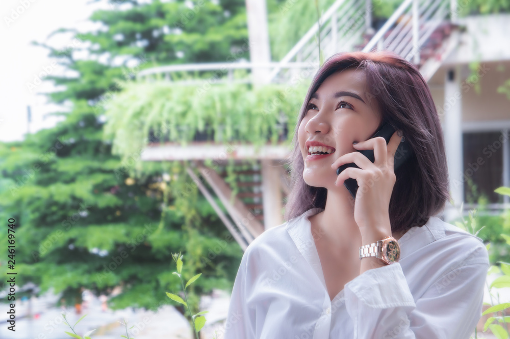 asain girl's smiling and using smart phone , happy time and taking mobile telephone asain girl's smiling and using smart phone , happy time and taking mobile telephone