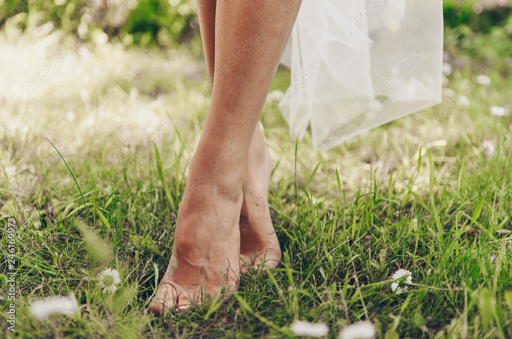 Bride barefoot bride stands on green grass where daisies grow Bride barefoot bride stands on green grass where daisies grow