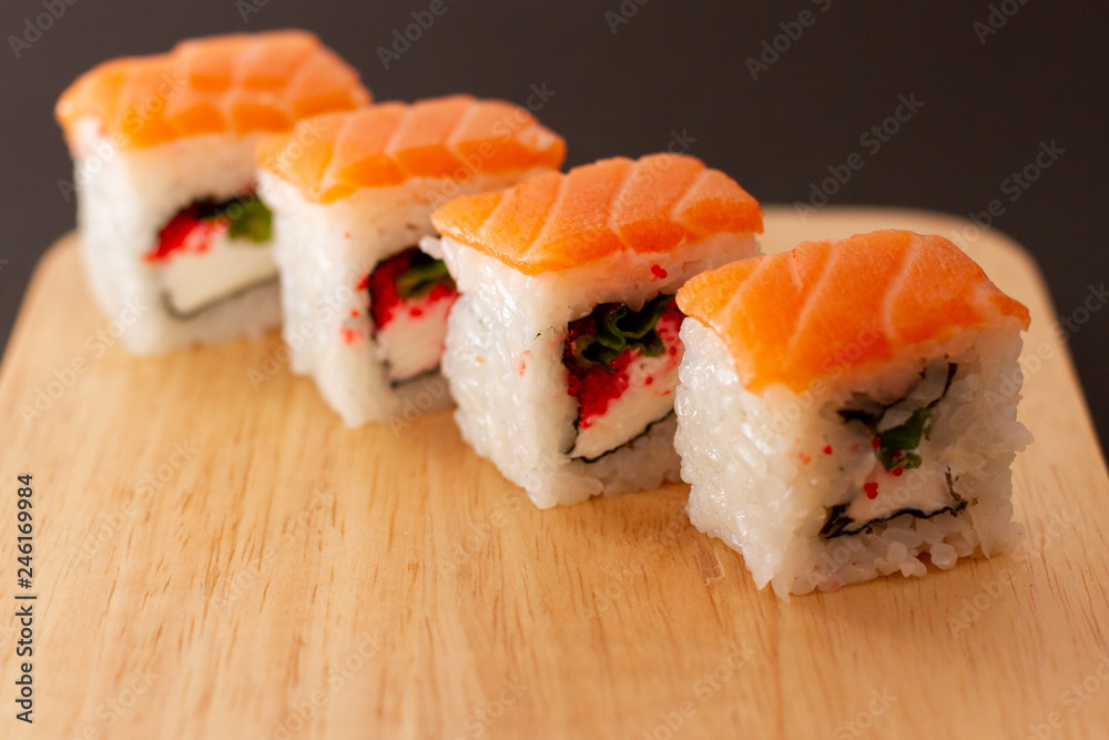 sushi roll with salmon on wooden board sushi roll with salmon on wooden board