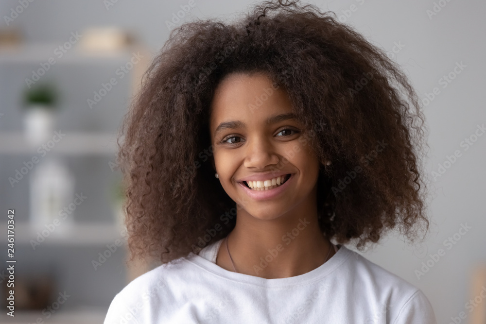 Portrait of happy African American teen girl looking at camera at home,  headshot of smiling black teenager posing indoors, beautiful mixed race  teenage female laughing making picture Stock Photo