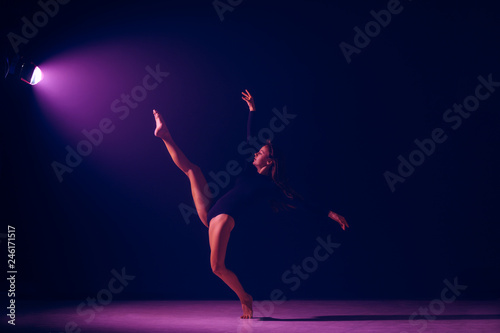Young female ballet dancer dancing on neon lights studio background. Ballerina project with caucasian model. The ballet, dance, art, contemporary, choreography concept