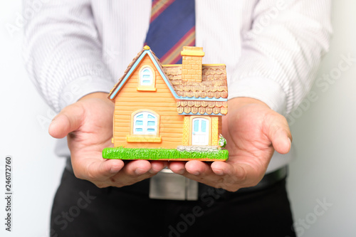 Estate agent holding home model in hand.