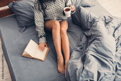 Woman in bed with book and cup of coffee