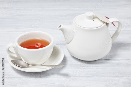 White tea cup with a spoon and a kettle (tea pot) isolated on white background. Teapot, spoon and tea cup. Isolated on white background