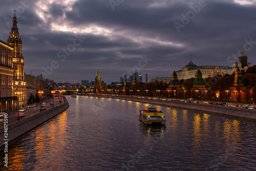 Pleasure boat on Moskva river near Moscow Kremlin in evening on a background of dramatic cloudy sky. City landscape