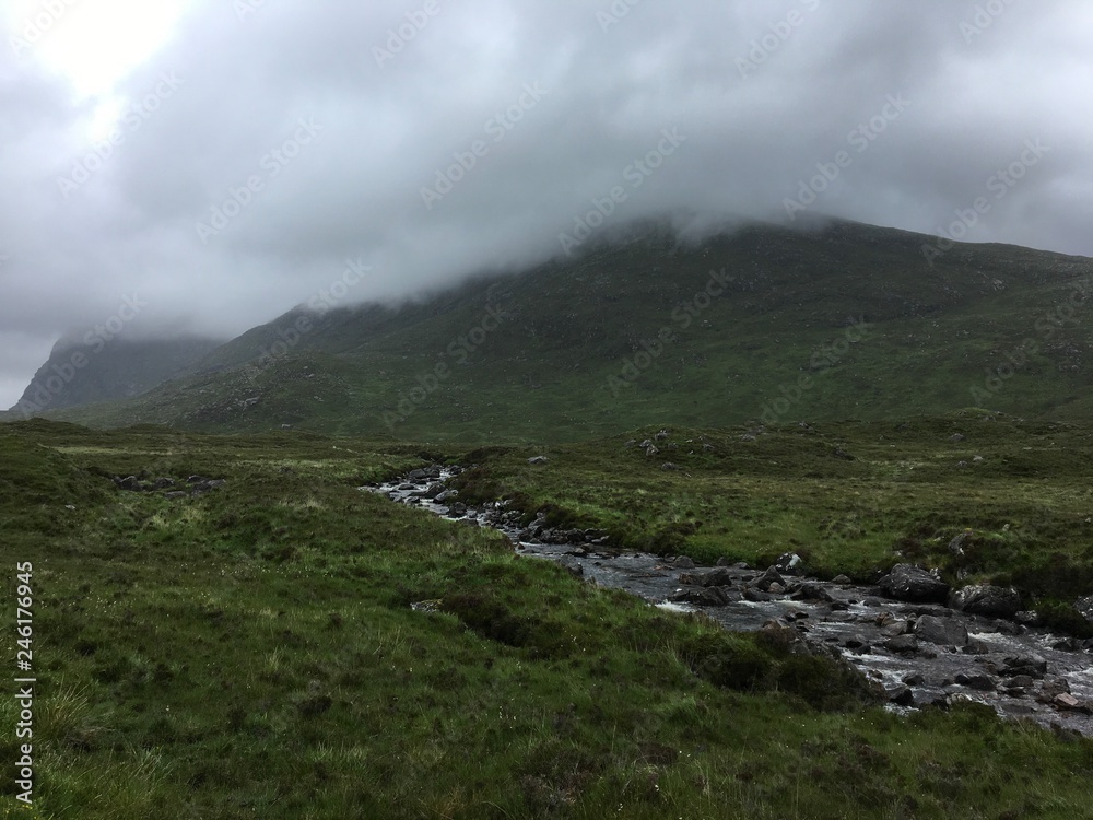 A scenic mountain footpath with a stream and a very stormy sky A scenic mountain footpath with a stream and a very stormy sky