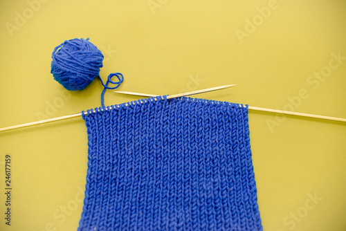 Bright knitted  scarf with knitting needles. On green background. Minimalism top view contrast. Horizontal vie several objects yellow background