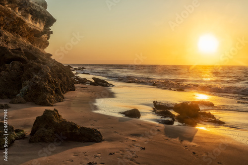 Beautiful sunset on the Namibe wild beach, Africa. Angola. With cliff and rocks. photo